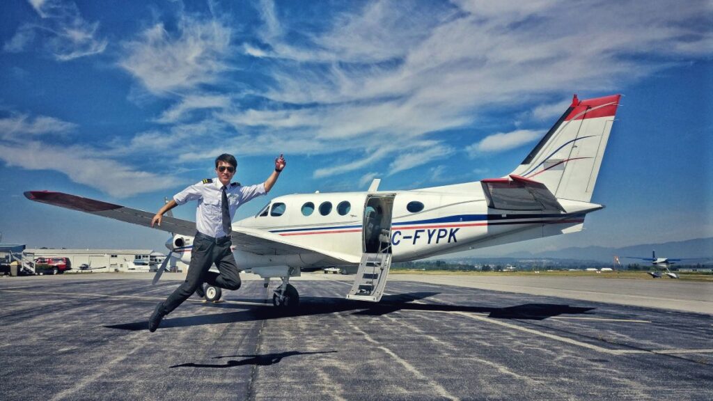 Pilot jumping at the side of a landed airplane
